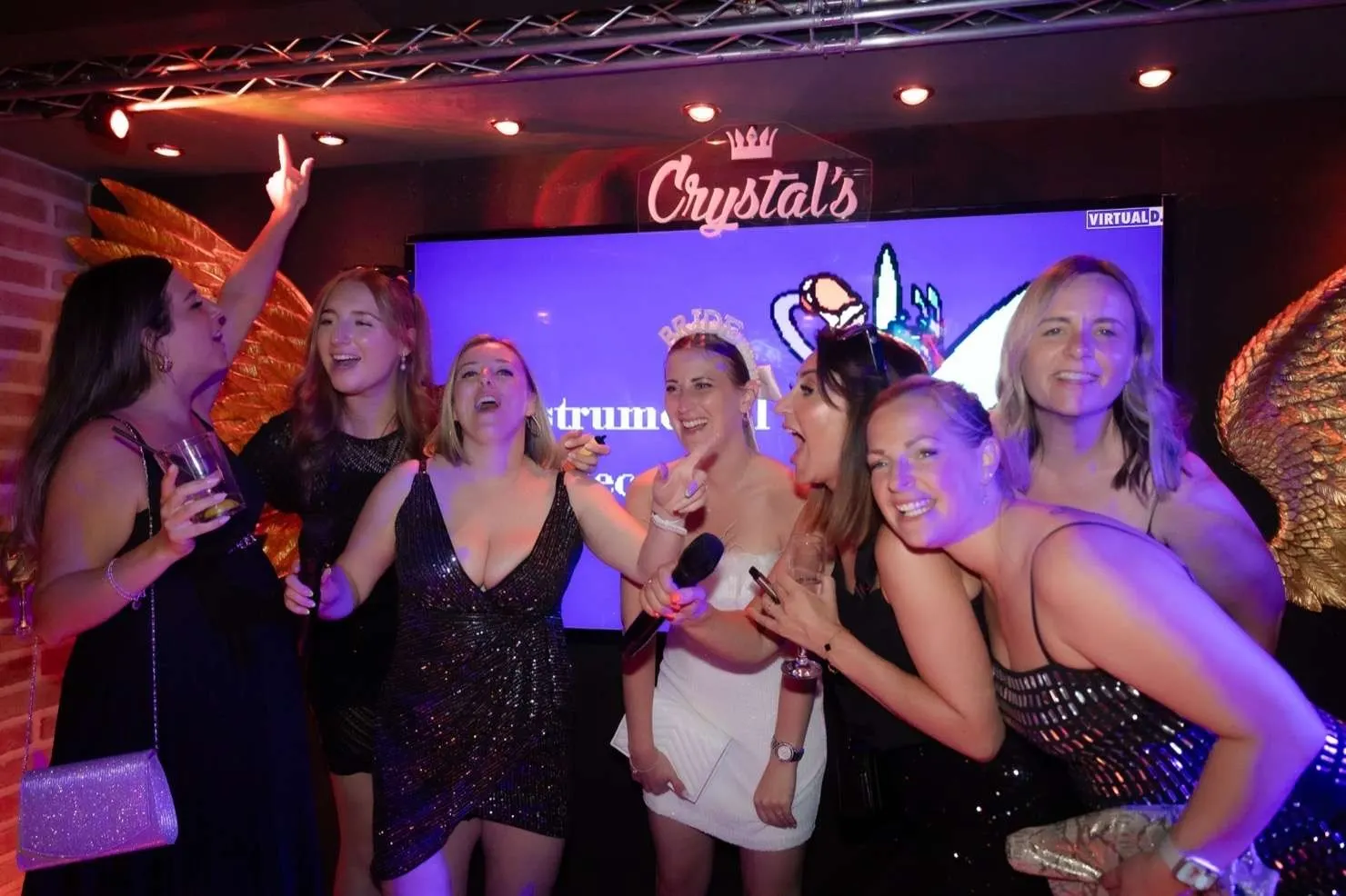 A hen party posing on stage in front of the Crystal's screen
